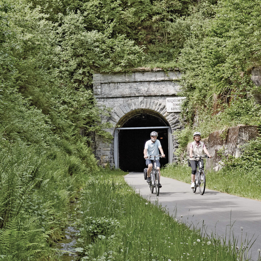 Fahrradfahrer fahren aus einem Tunnel.